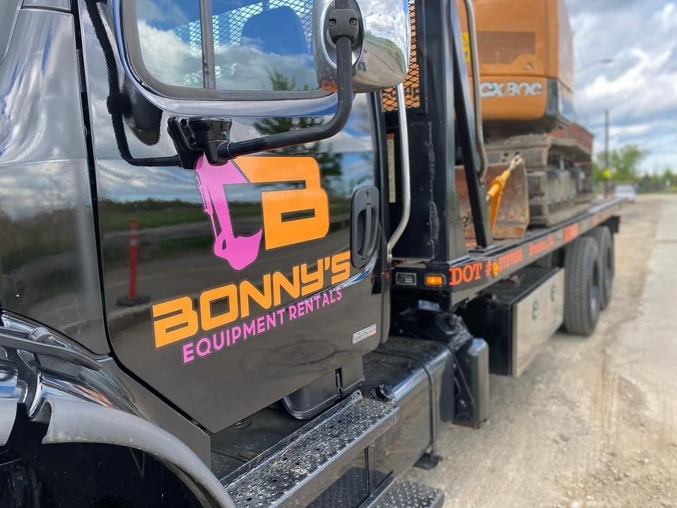 Black truck cab with BONNY’S Equipment Rentals logo parked beside heavy equipment on a dirt road