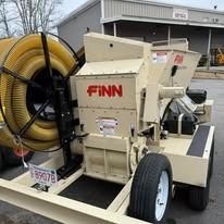 Beige FINN industrial machine with large yellow hose on a trailer outdoors