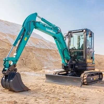 Turquoise excavator with a bucket on sandy ground at a construction site