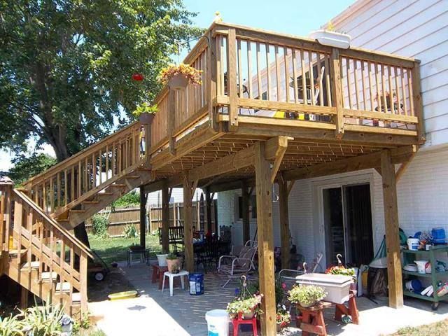 A deck with stairs leading up to it next to a house.