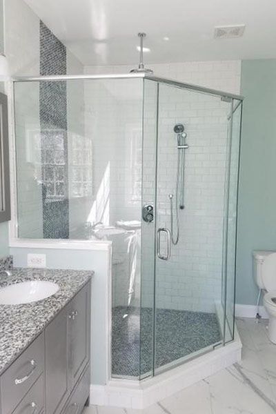 A bathroom with a walk in shower , sink , toilet and mirror.