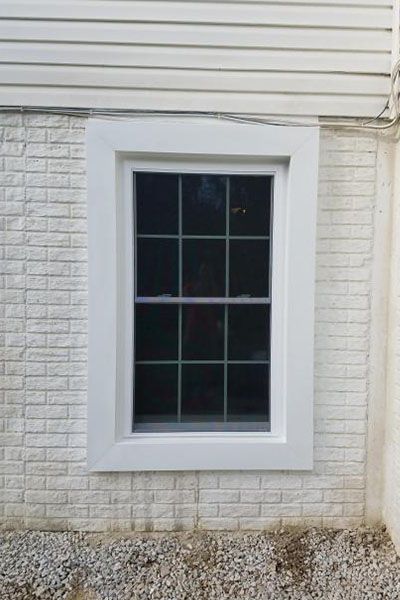 A window on the side of a white brick building.