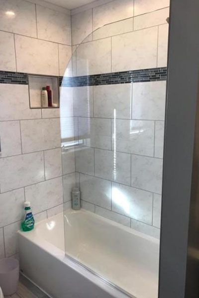 A bathroom with a bathtub and a glass shower door.