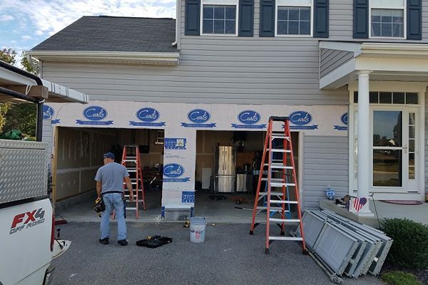 A man is working on a garage door with a ladder