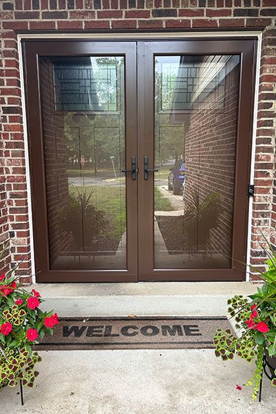 A welcome mat is on the porch of a brick house.