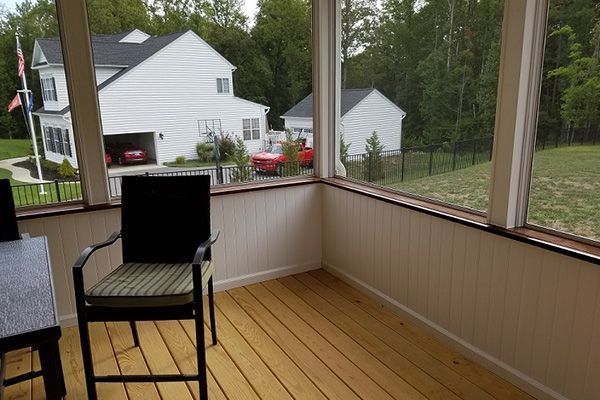 A screened in porch with chairs and a table
