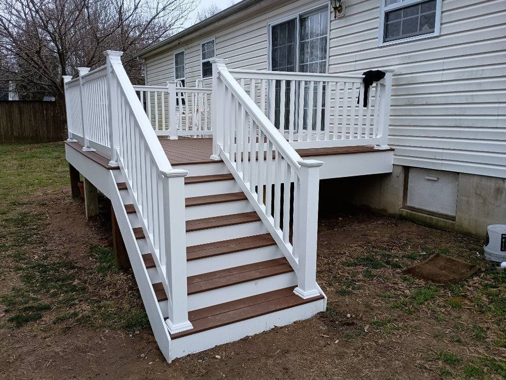A deck with stairs leading up to it and a white railing.