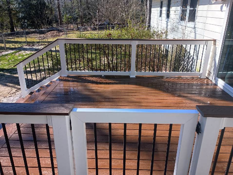 A wooden deck with a white railing and a gate.