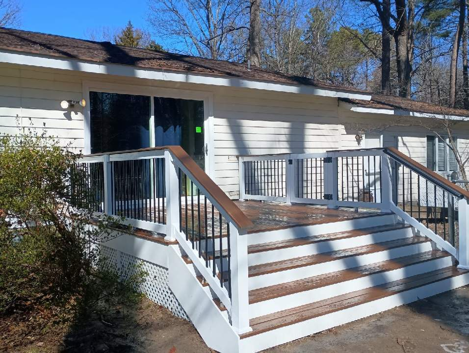 A white house with a wooden deck and stairs