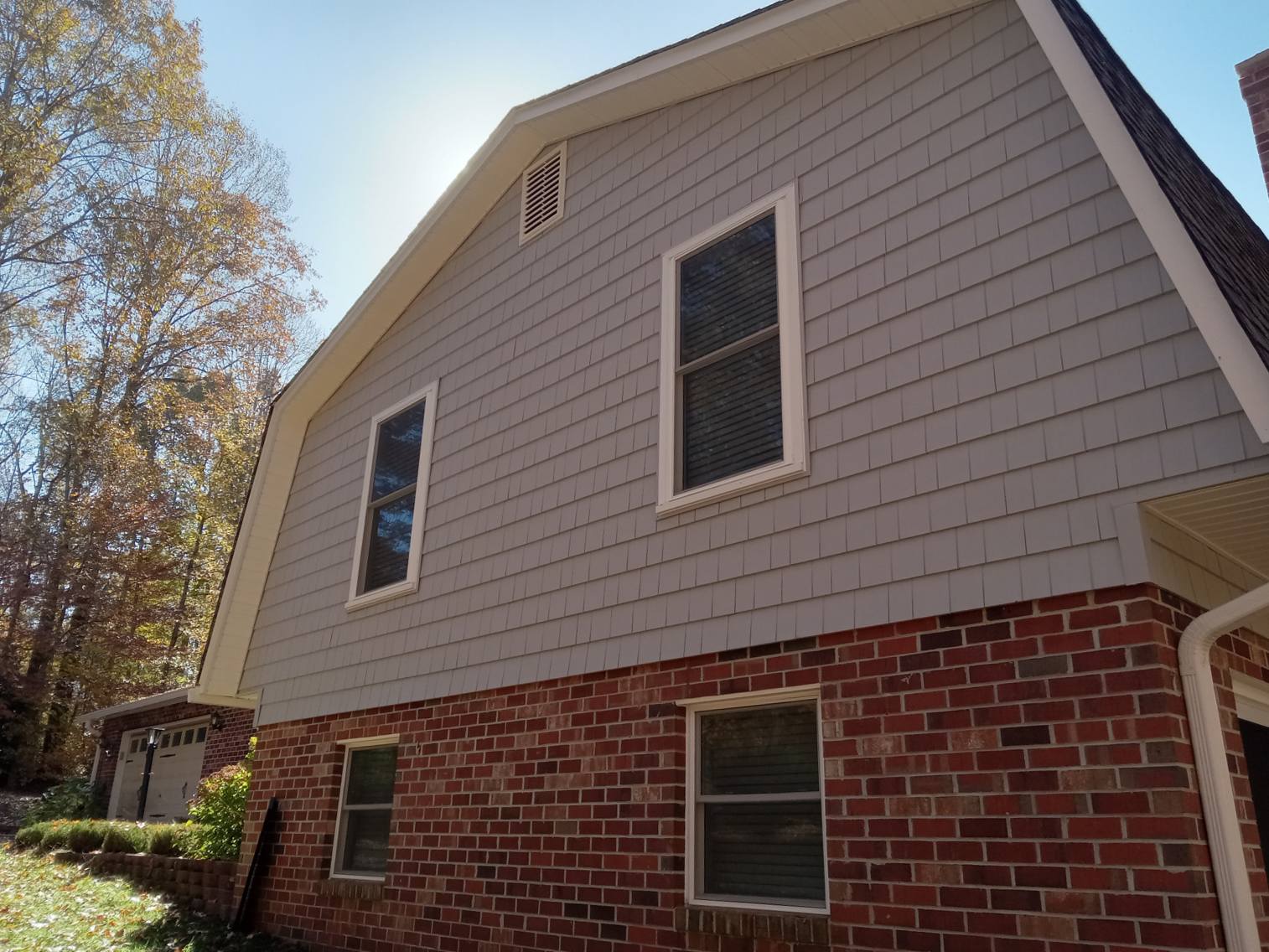 A brick house with a gray siding and white trim
