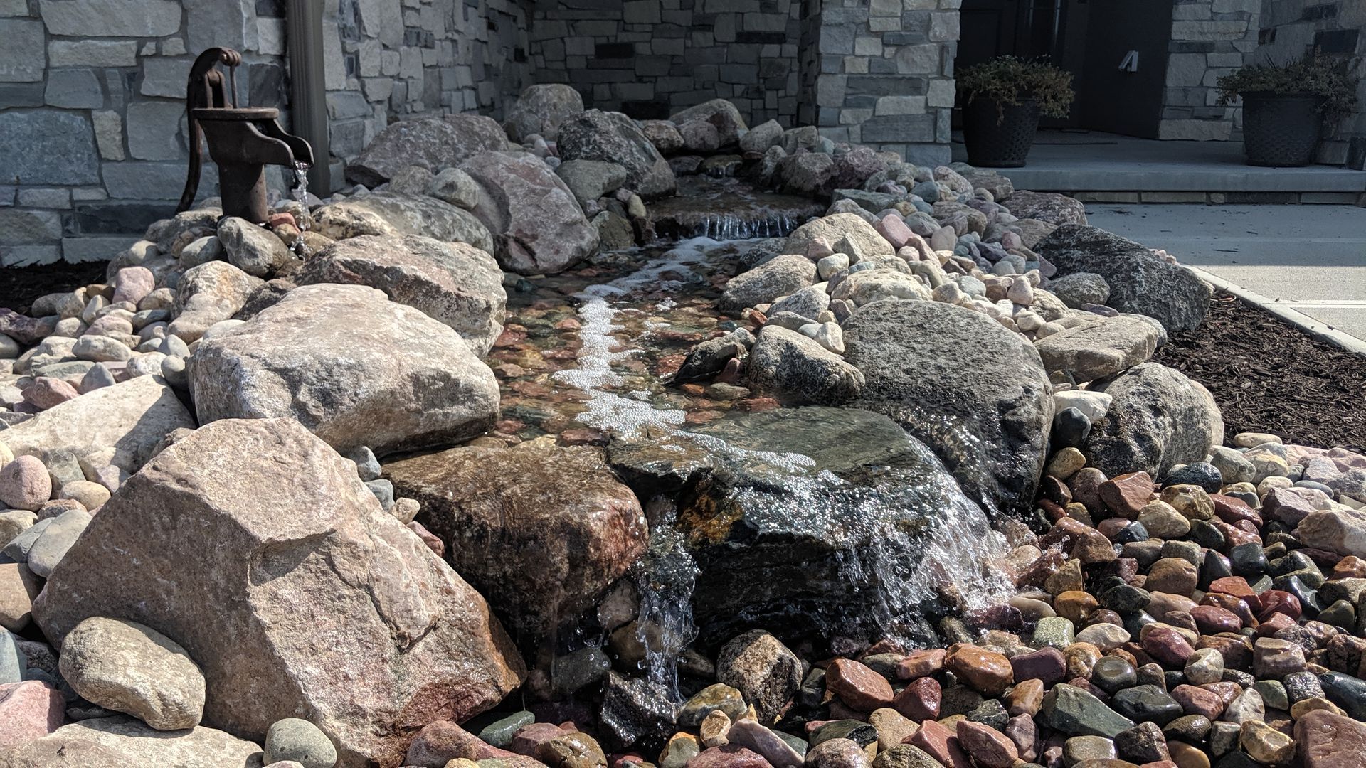 Water feature with flowing water cascading over rocks. Black pump next to waterfall.
