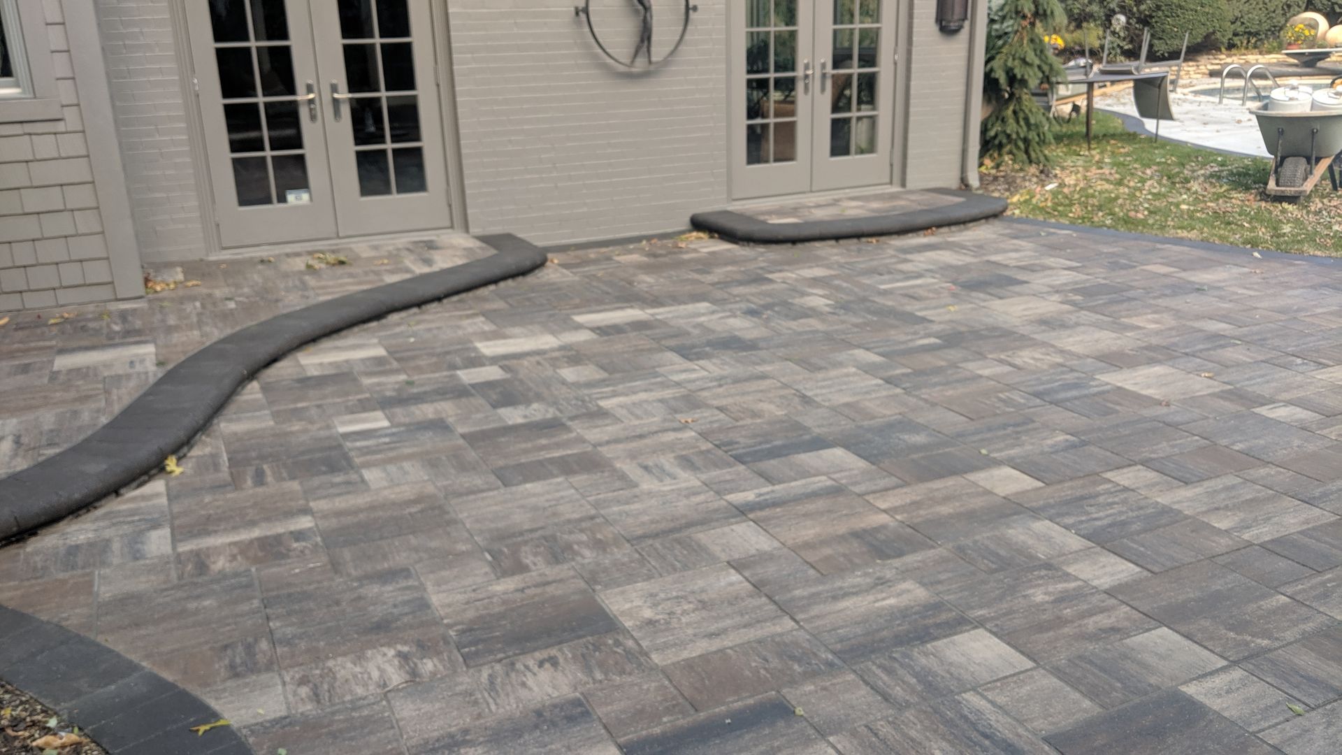 Stone patio with French doors, drain pipe, and small concrete stoops.