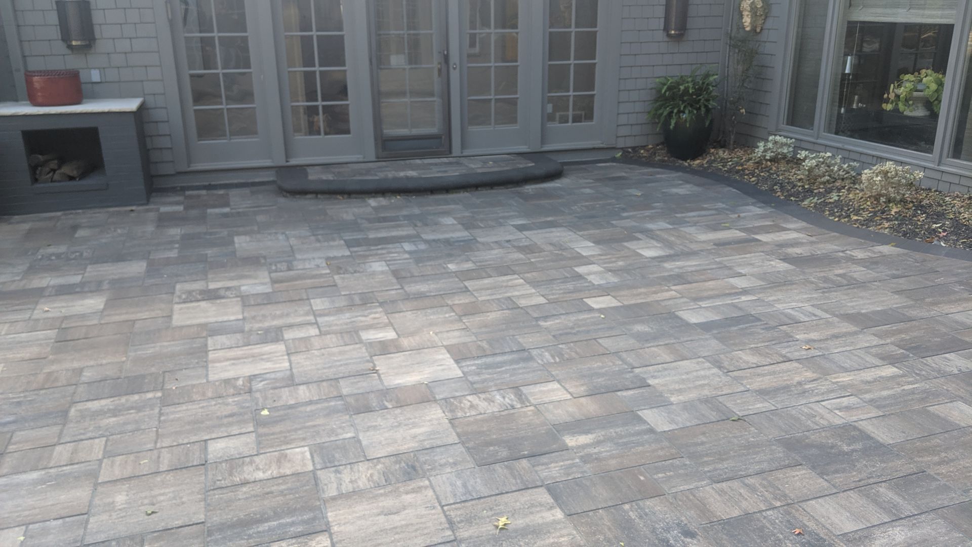 Gray brick patio in front of a house with French doors.