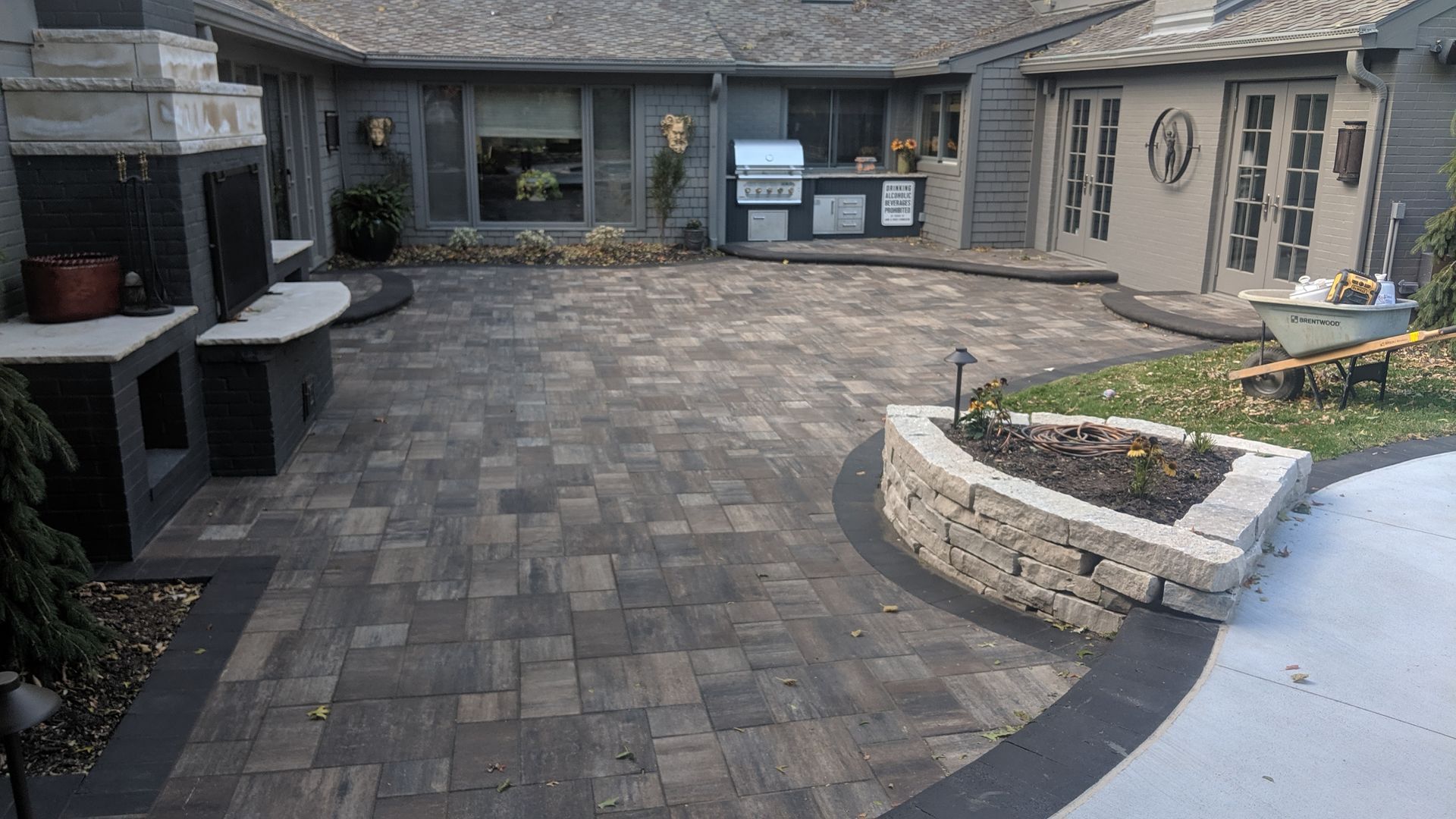 Patio with gray pavers, built-in grill, fireplace, and raised garden bed.