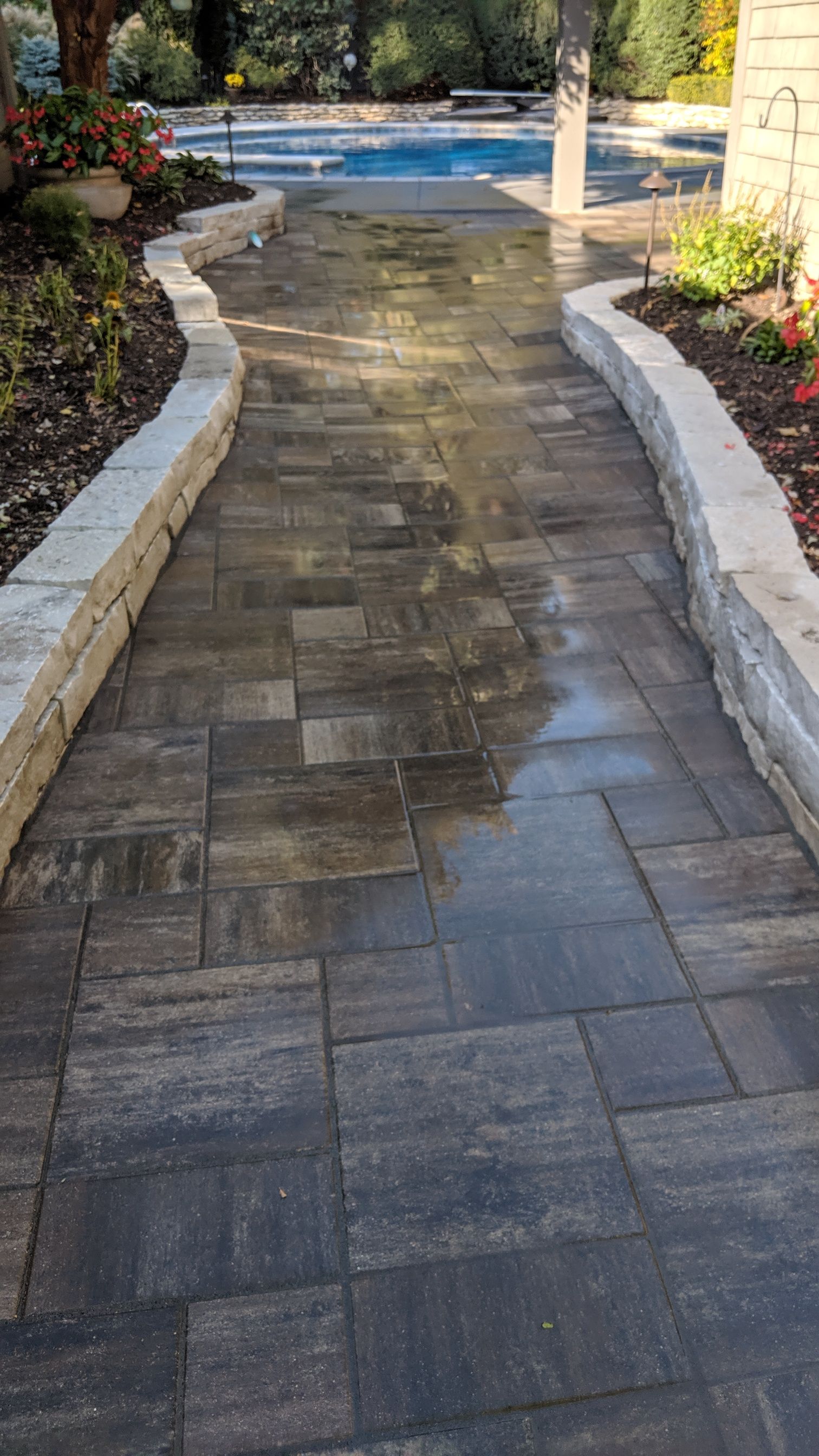 Brick pathway with stone borders leading to a pool.