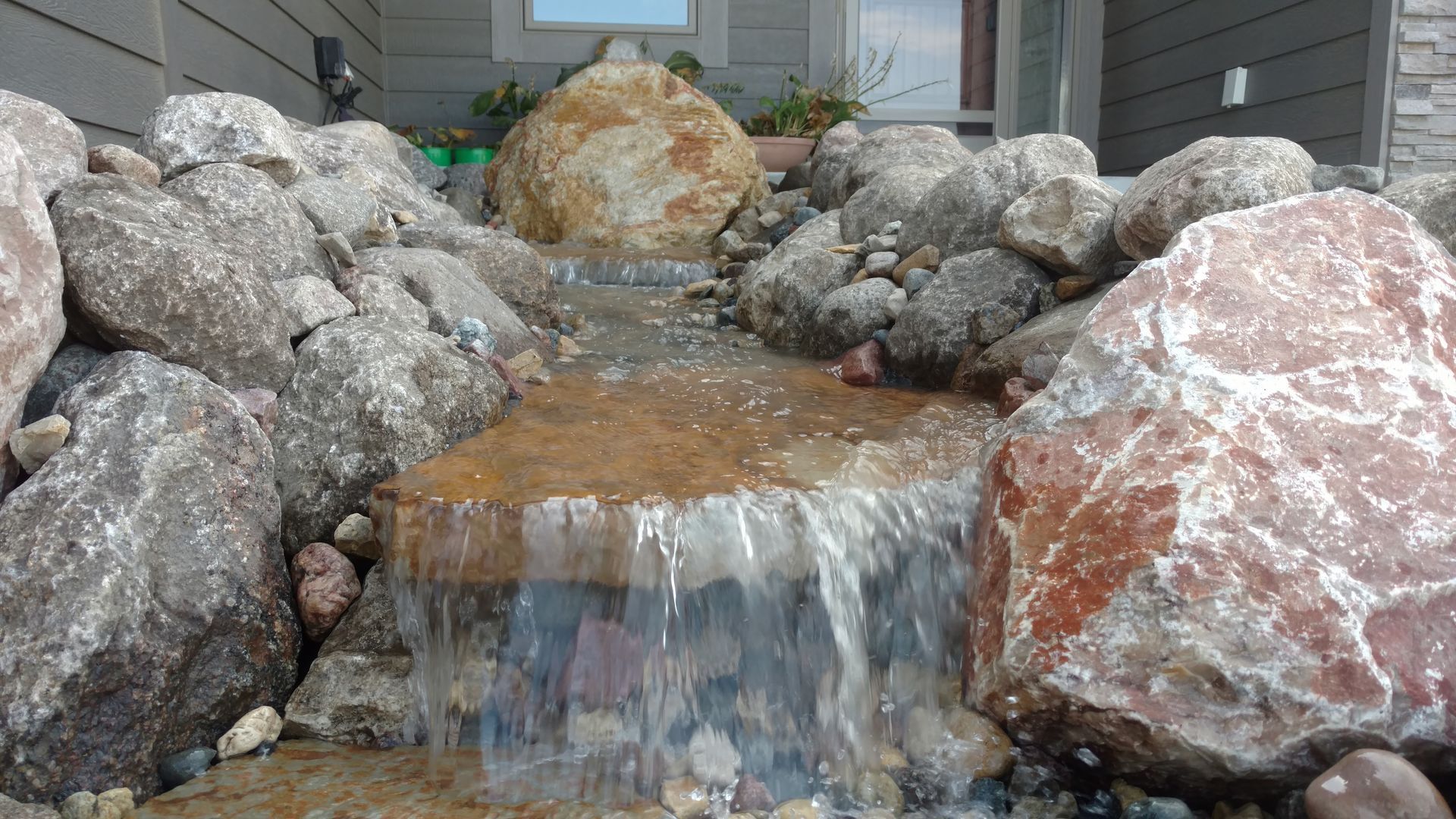 Water cascading over rocks in a decorative outdoor water feature.