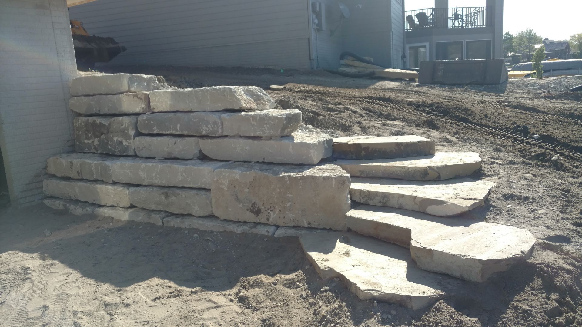 Stone steps leading up, constructed next to a building on a dirt surface.