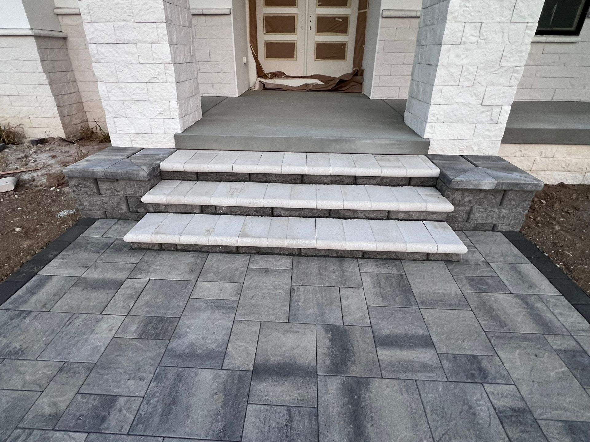 Stone steps and walkway leading to a house entrance with pillars and a doorway.