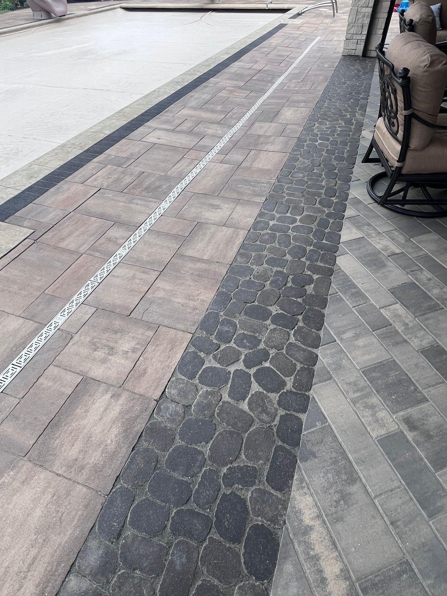 Patio pathway with various stone textures and a drainage channel.