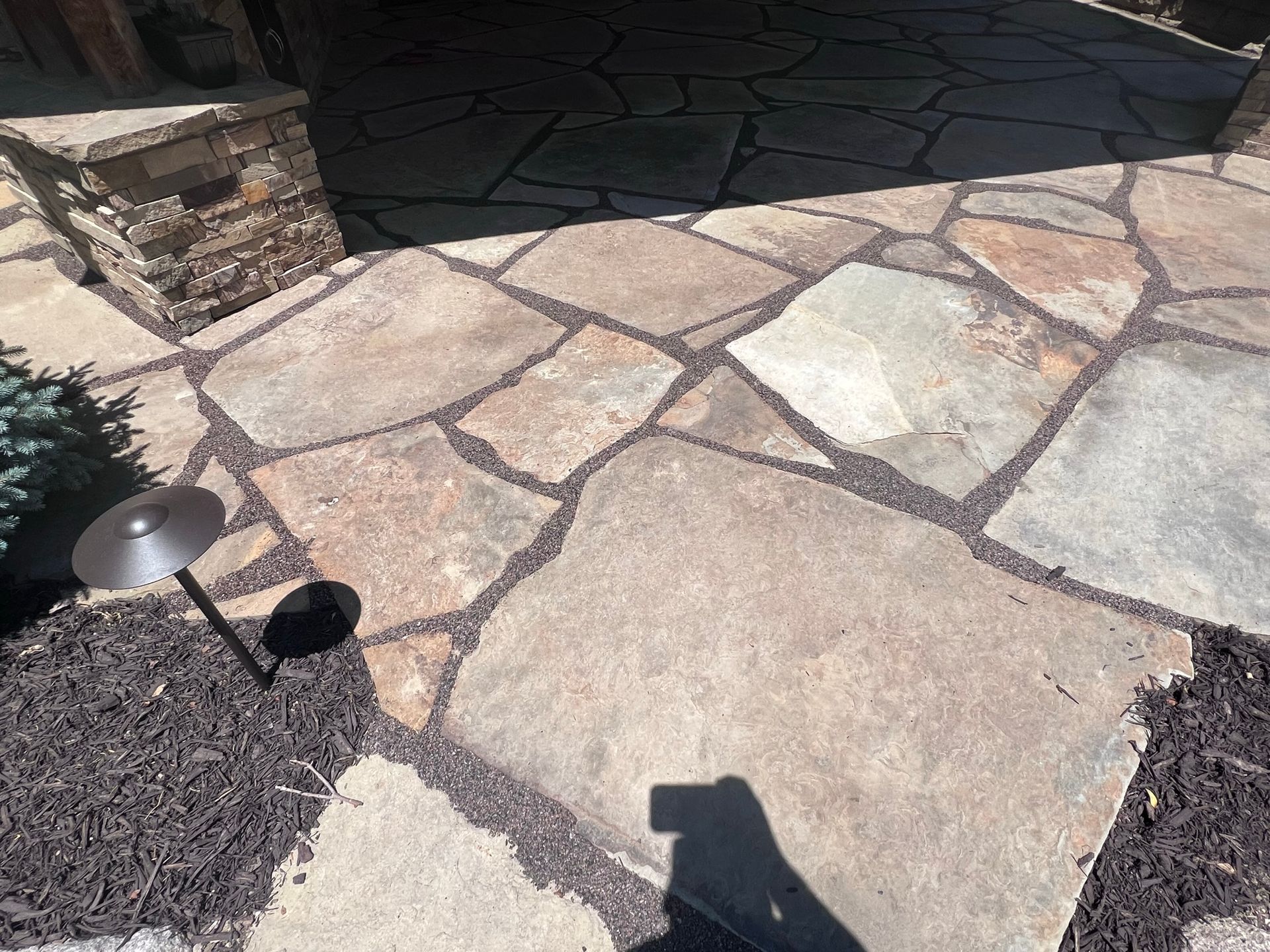 Flagstone patio with dark gravel joints and a small landscape light.