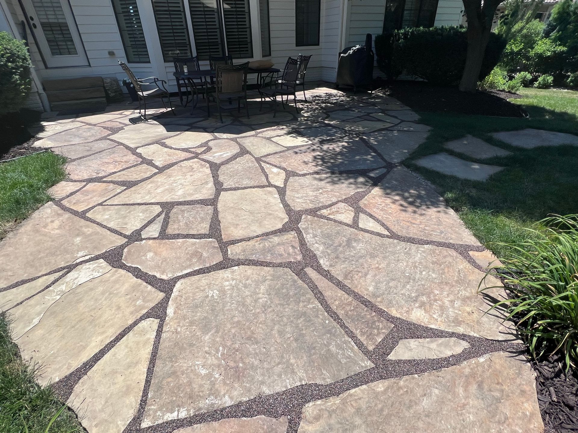 Flagstone patio with dark gravel joints in a backyard setting.