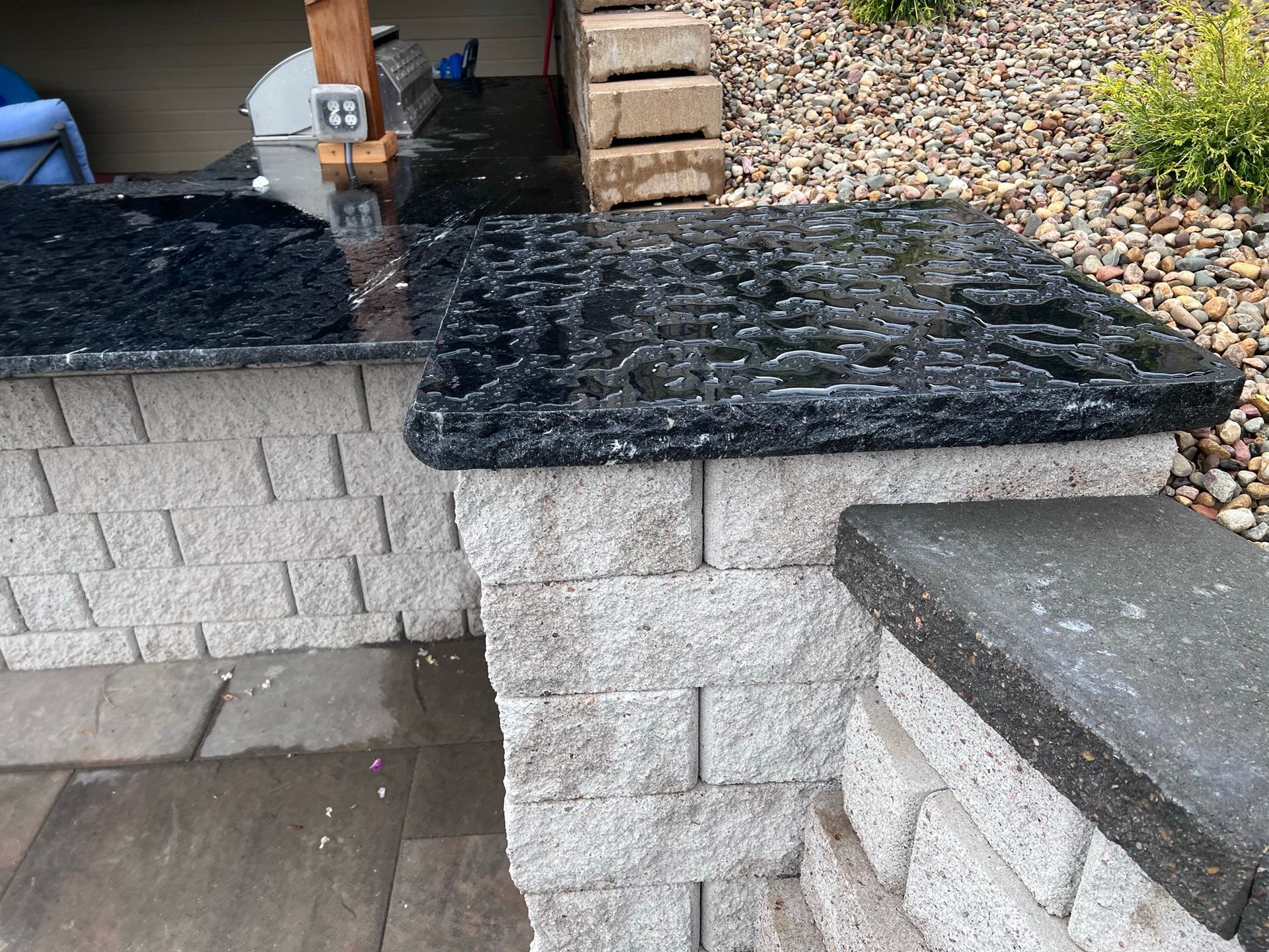 Stone countertop on a brick structure, dark stone surface, water.