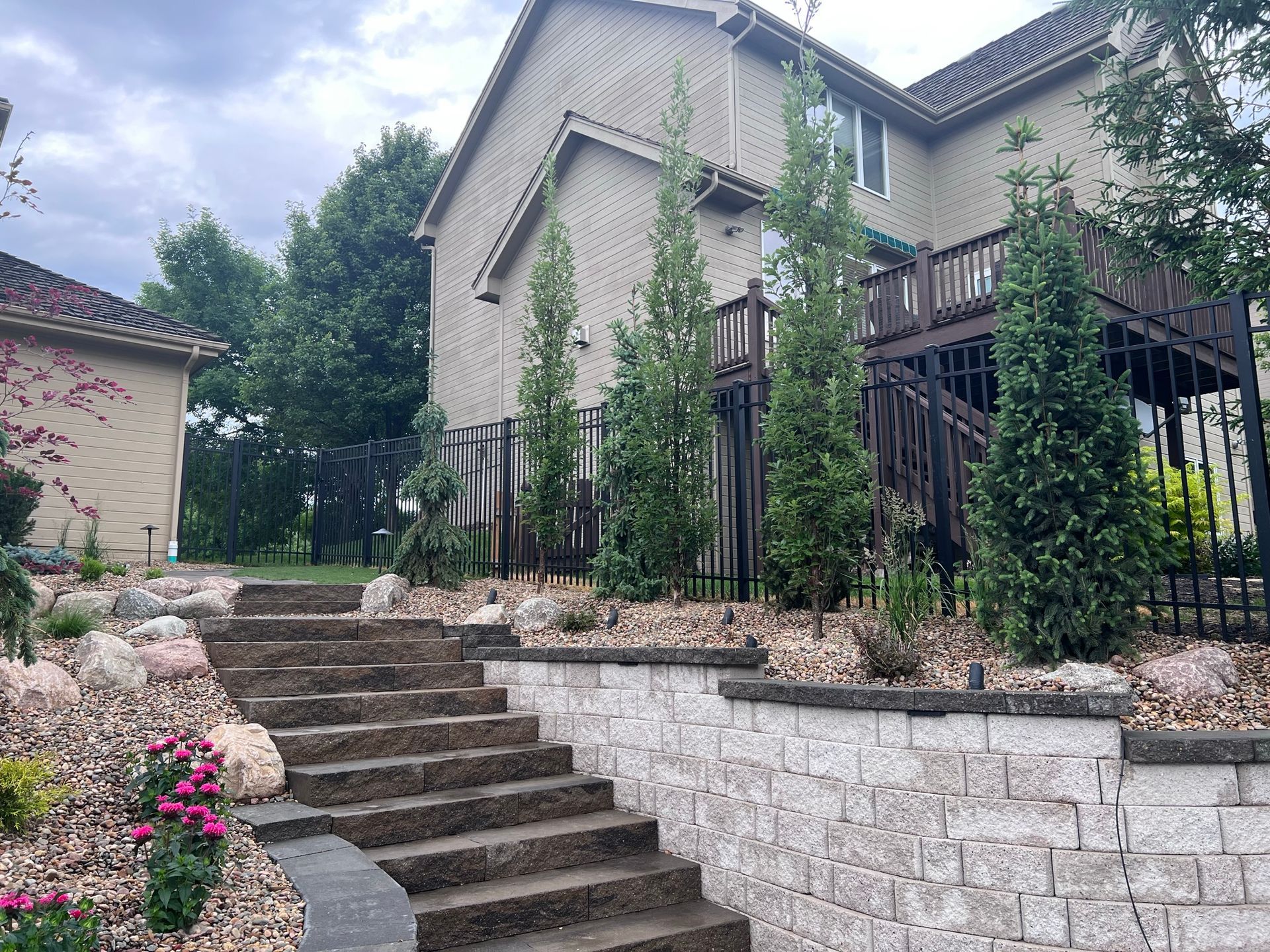 Stone staircase leading up to a house with a wooden deck and landscaping.