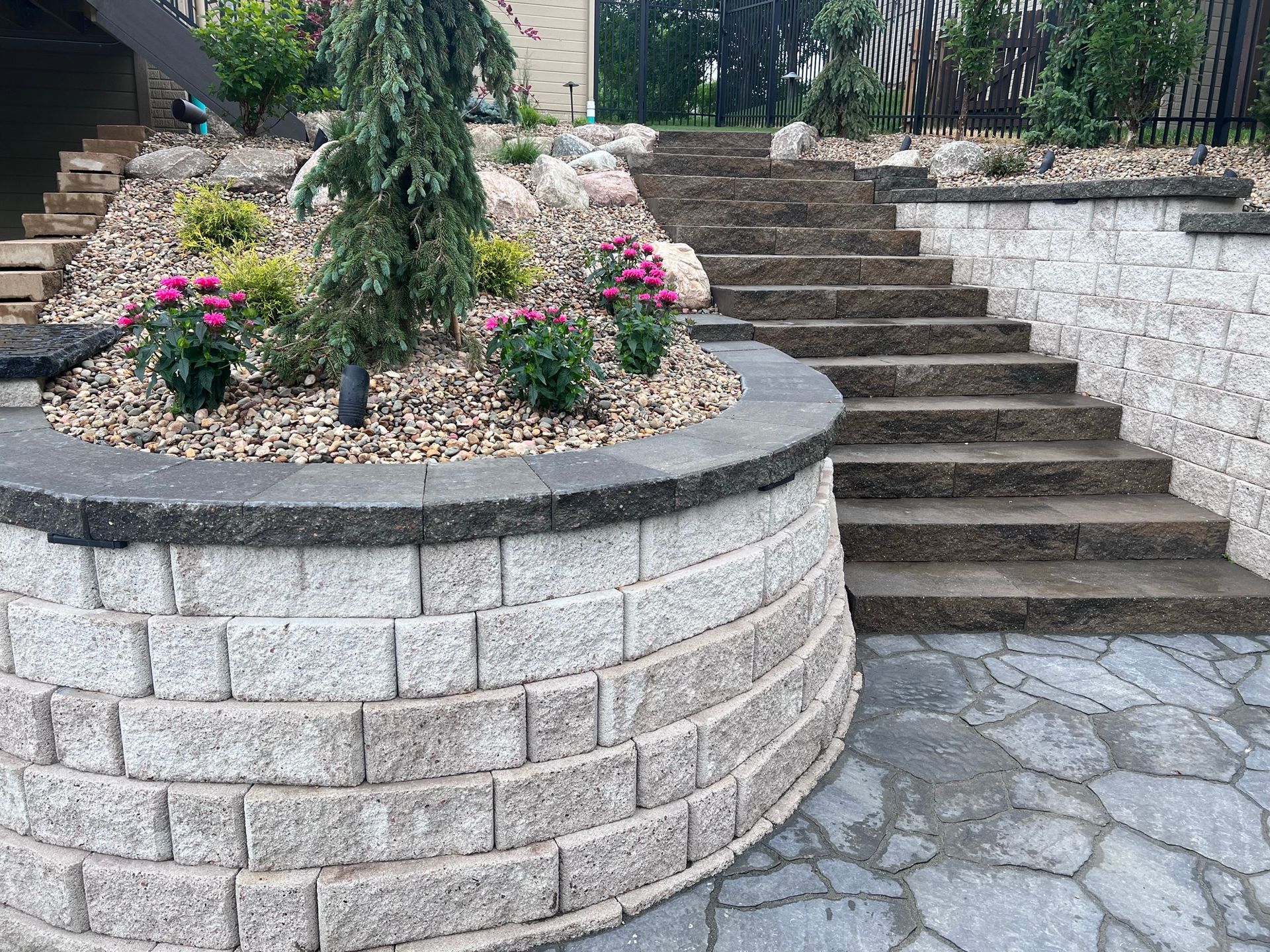 Stone retaining wall with steps, garden, and plants; outdoor setting.