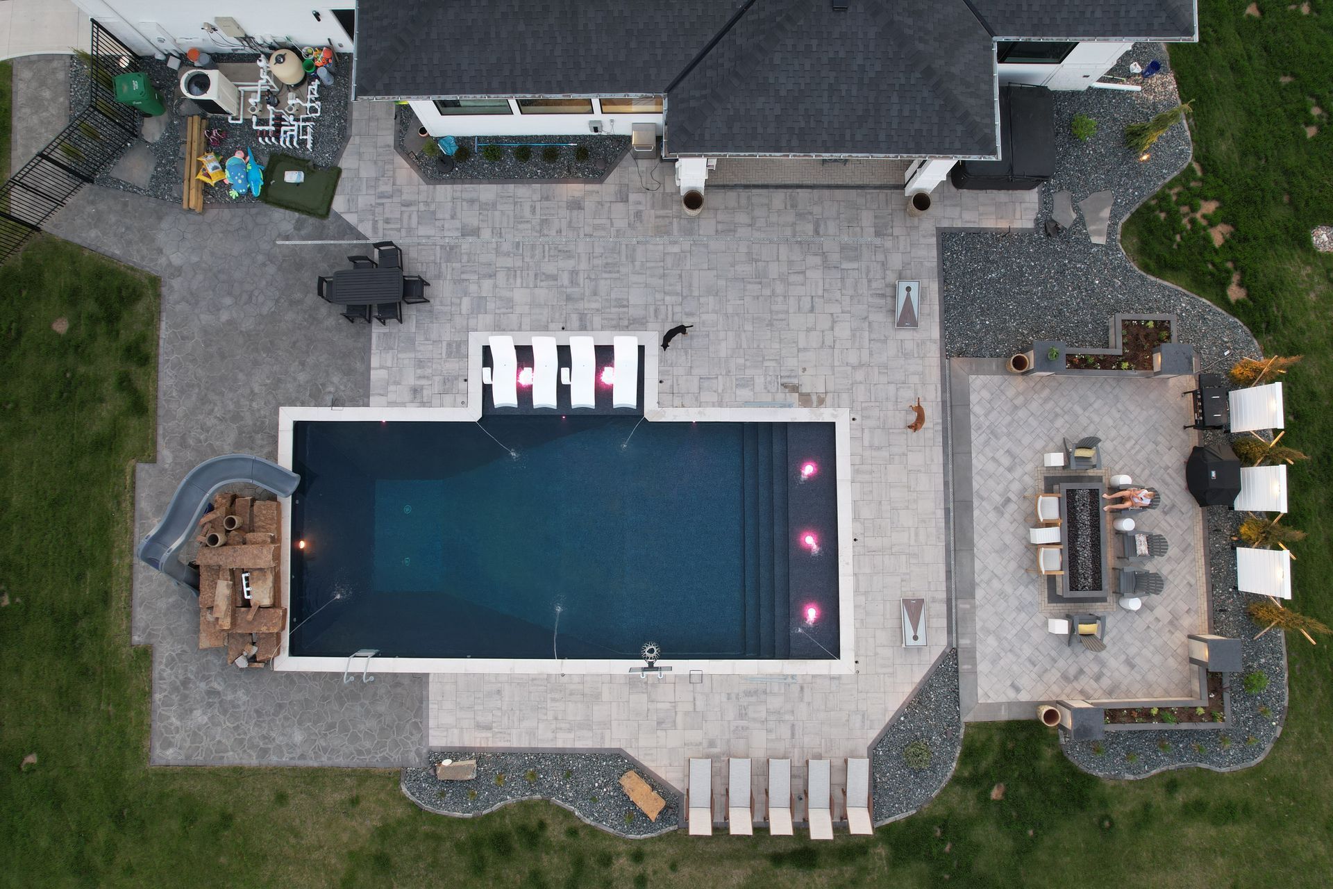 Aerial view of a modern backyard with a pool, patio, and seating areas.