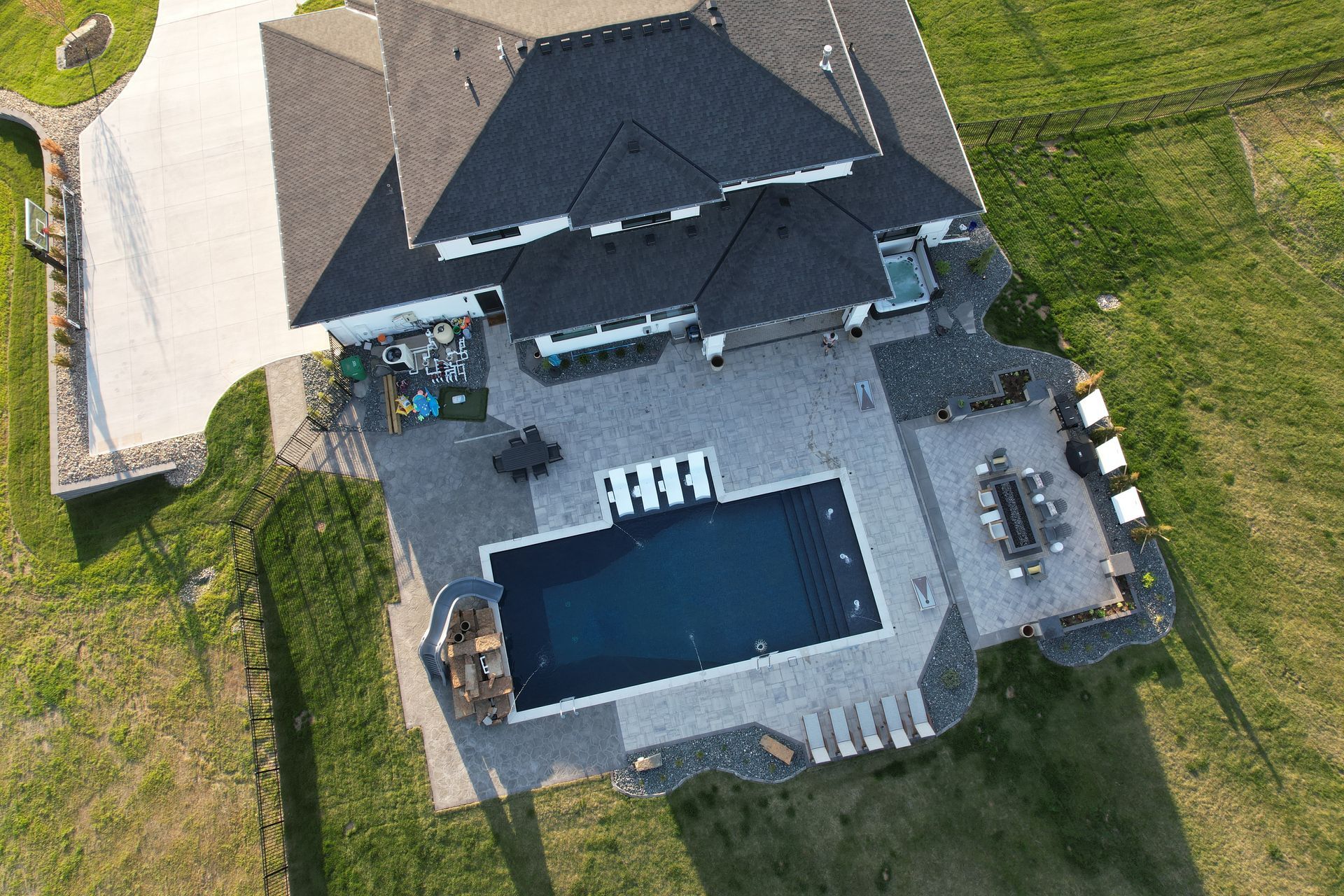 Aerial view of a large home with a pool and patio on a grassy lawn.