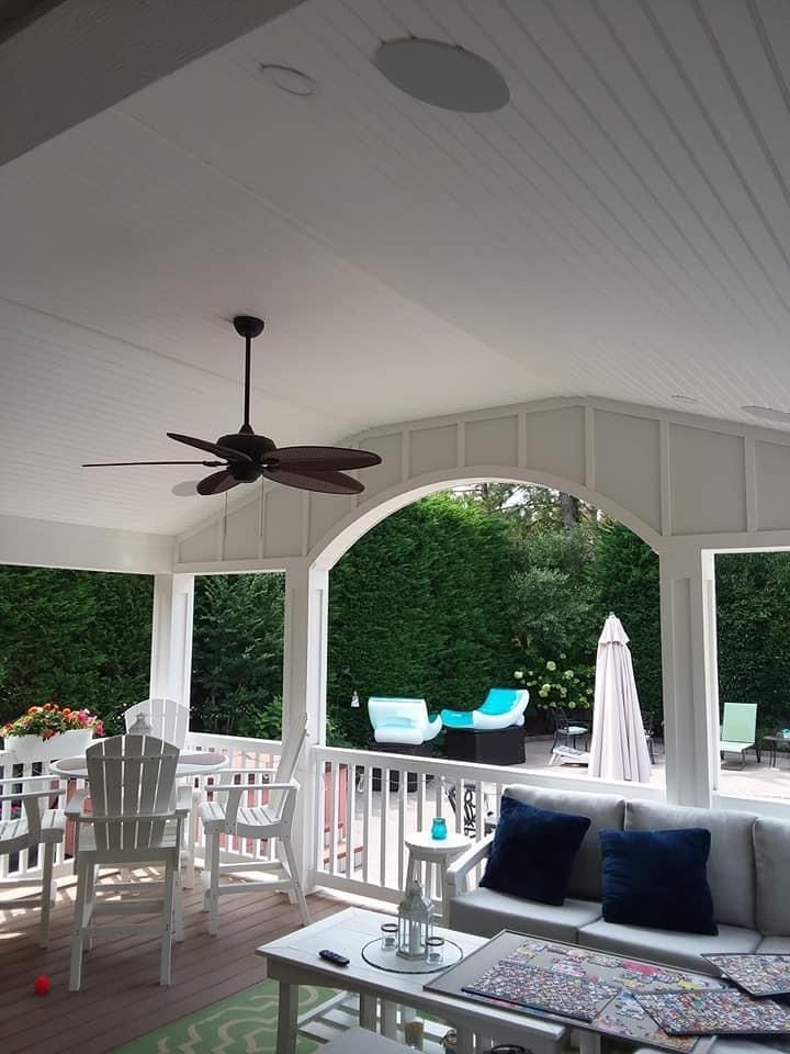 a porch with a ceiling fan and a couch and chairs