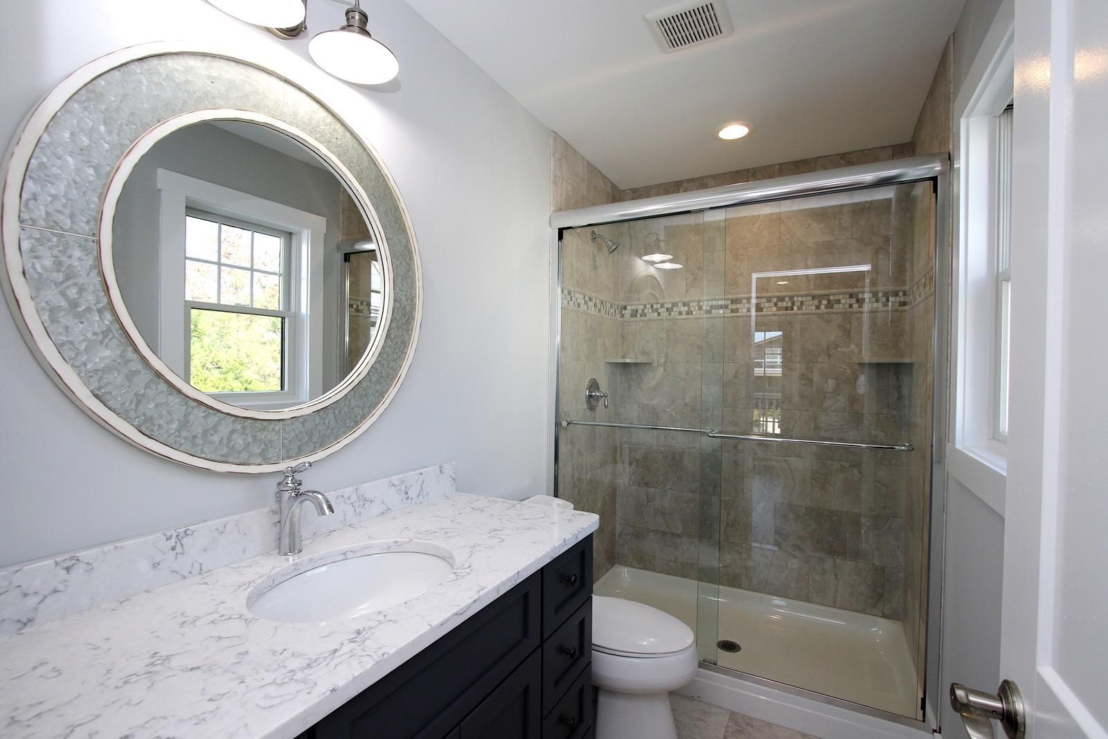 a bathroom with a toilet , sink , mirror and shower .