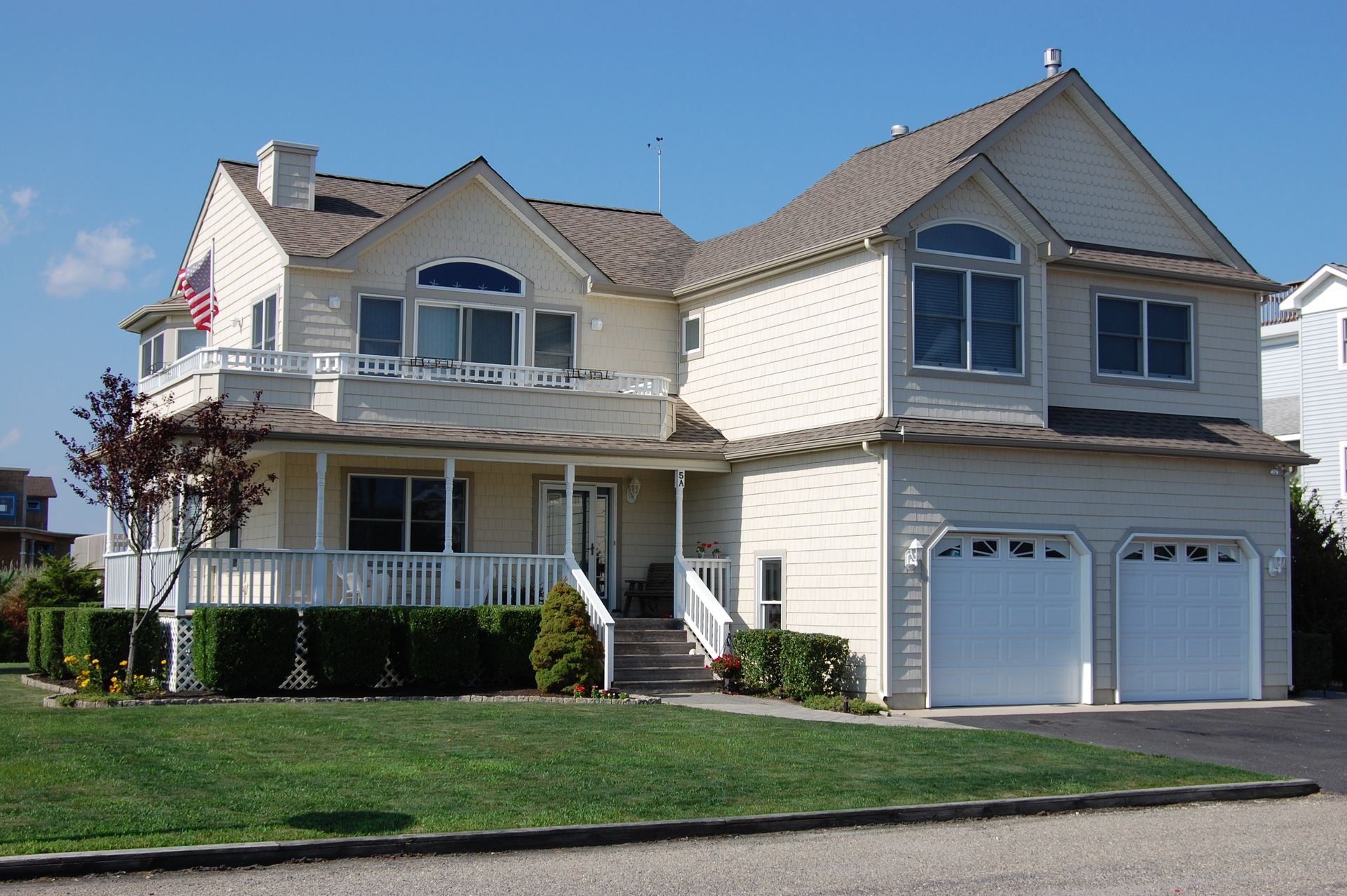 a large white house with two garage doors and a large porch