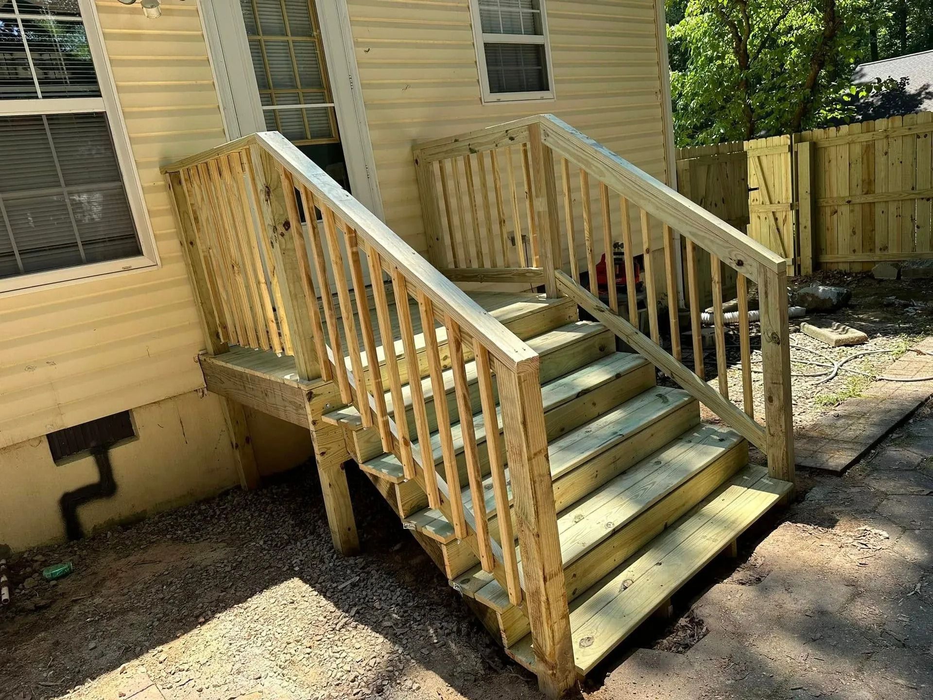 Wooden stairs and railing leading up to the back door of a yellow house.