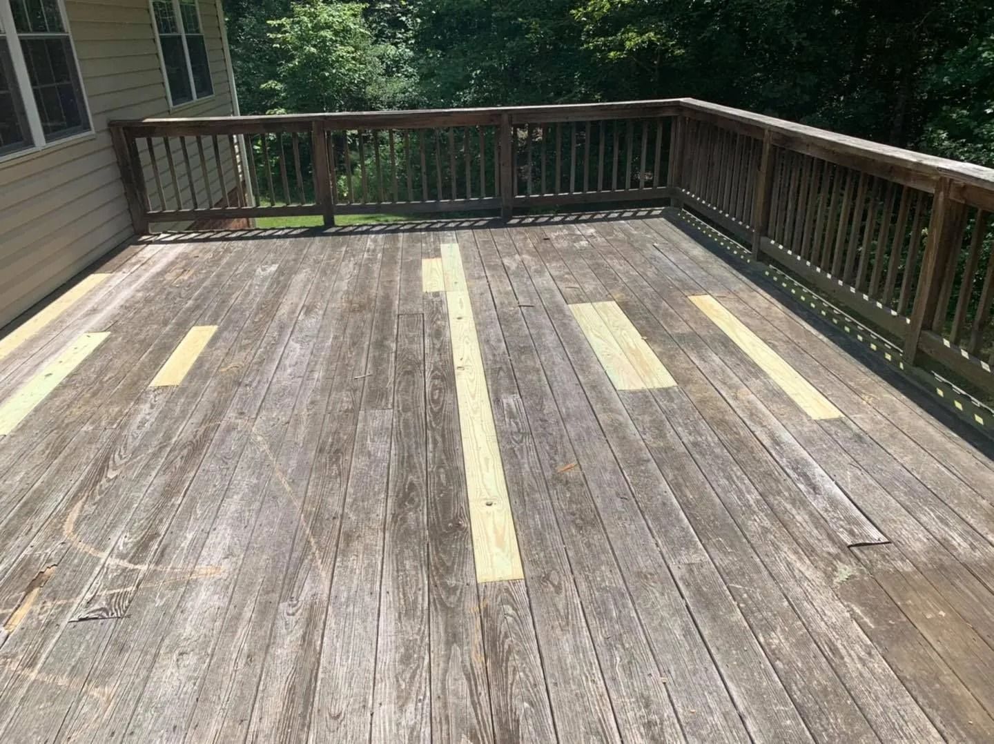 Weathered wooden deck with several new, lighter wood planks installed.