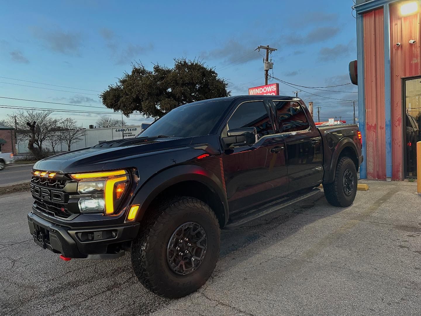 Black pickup truck parked beside a building at dusk