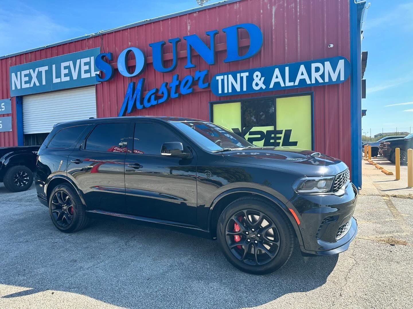 Black SUV parked outside Next Level Sound Master Tint & Alarm storefront