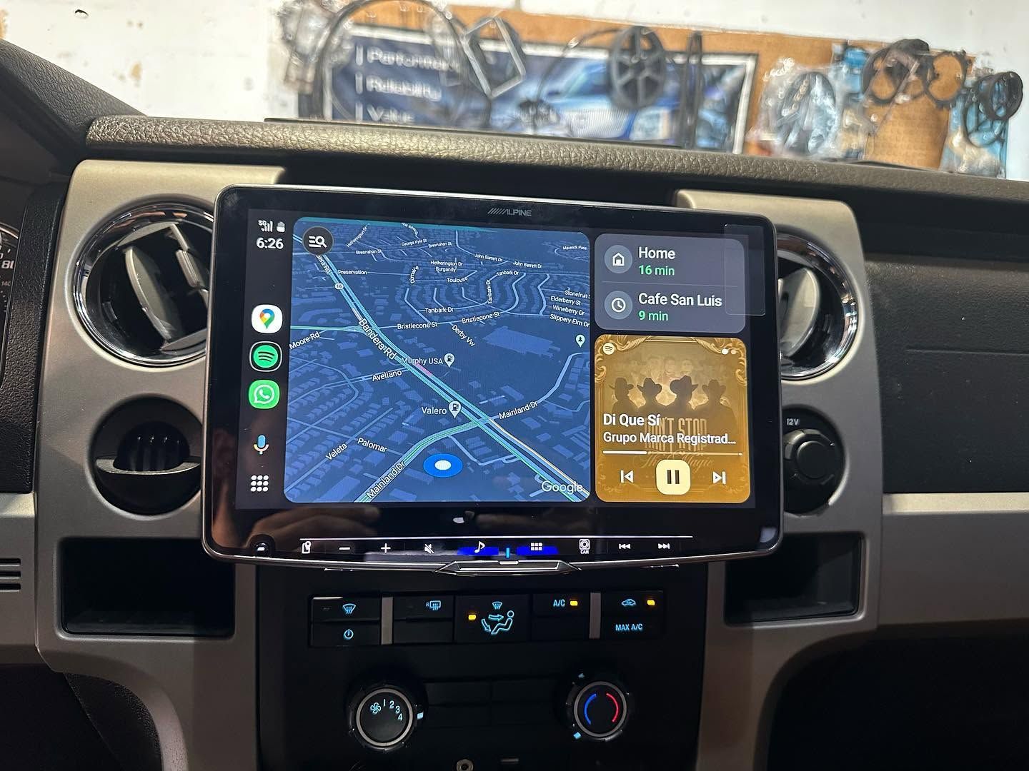 Car dashboard with a phone mounted on a navigation screen showing a map and music controls.
