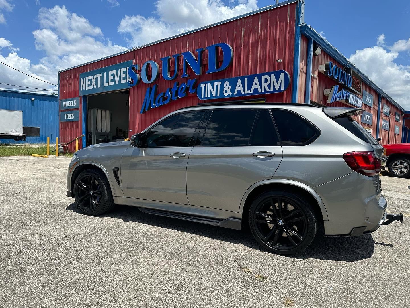 Silver SUV parked outside a red building with large “Sound” signage under a blue sky