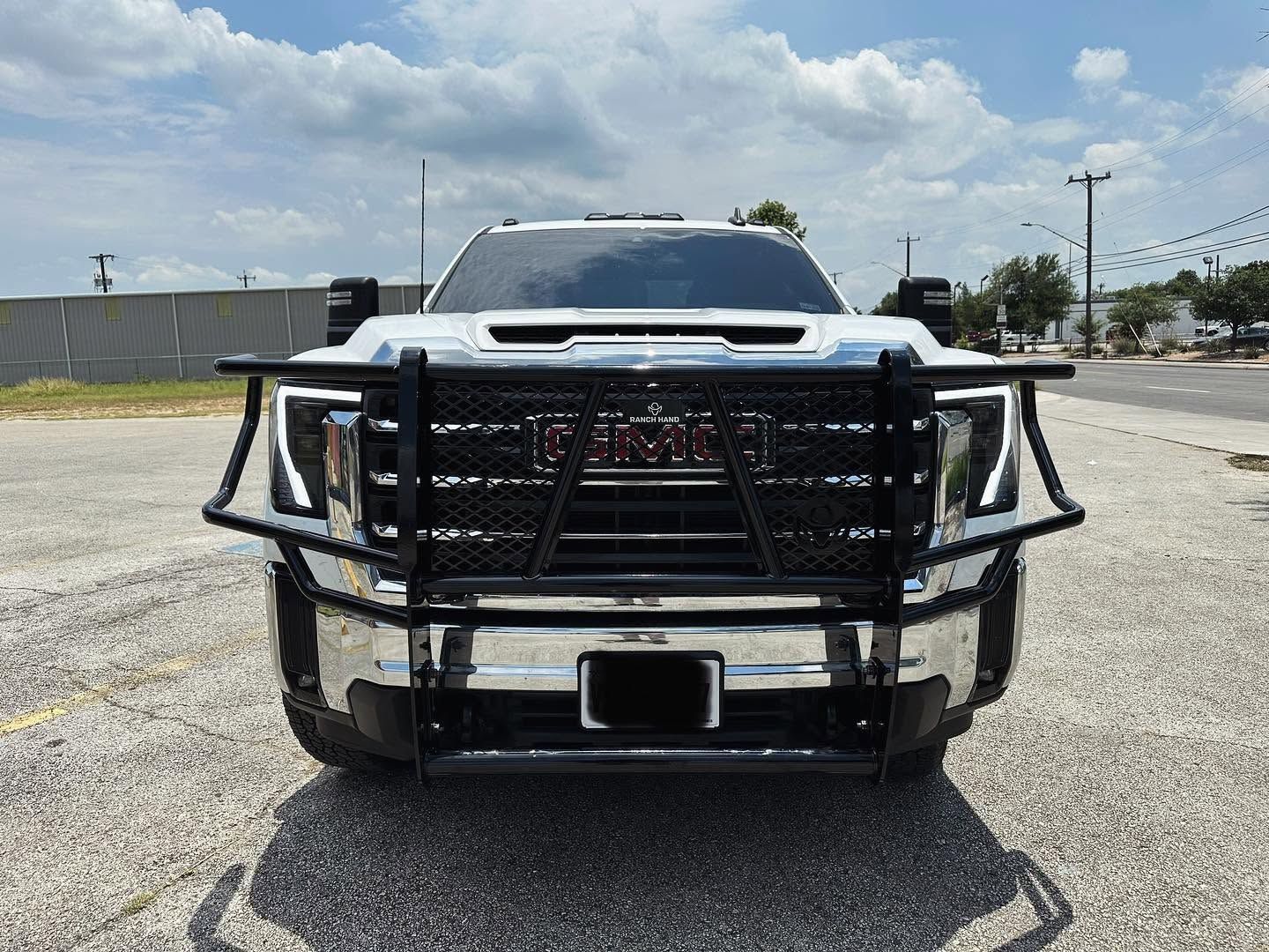 Front view of a white SUV with a heavy-duty black grille guard in a parking lot