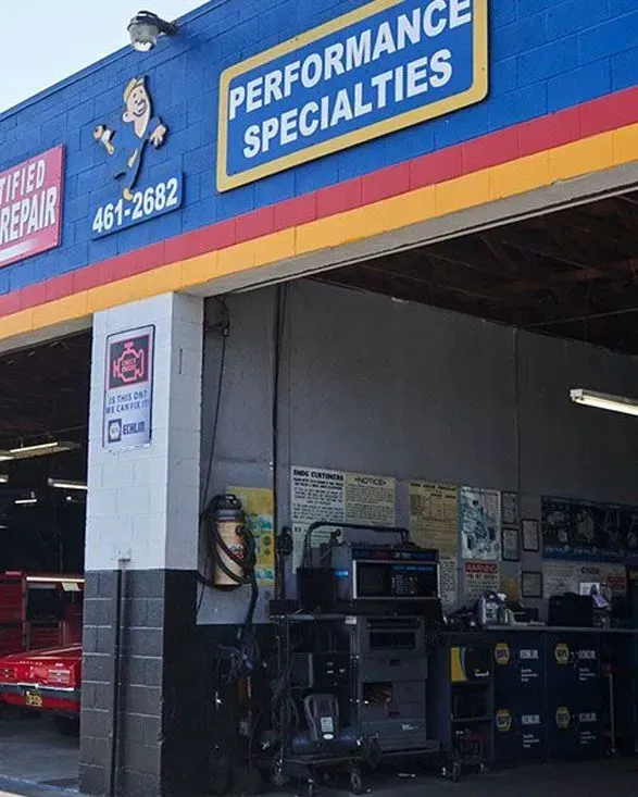 Auto shop storefront with blue “Performance Specialties” sign and open garage bay