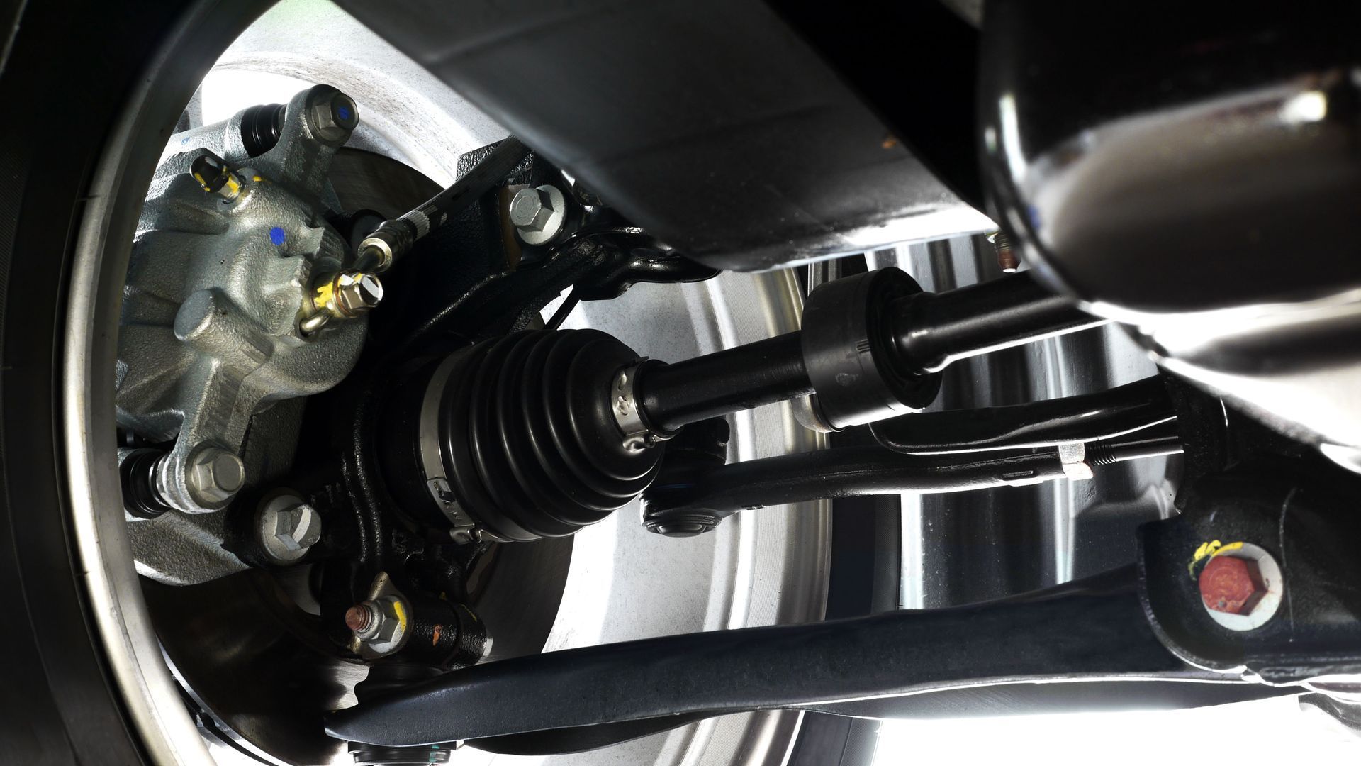 Close-up of a car’s front suspension and CV axle under the wheel well