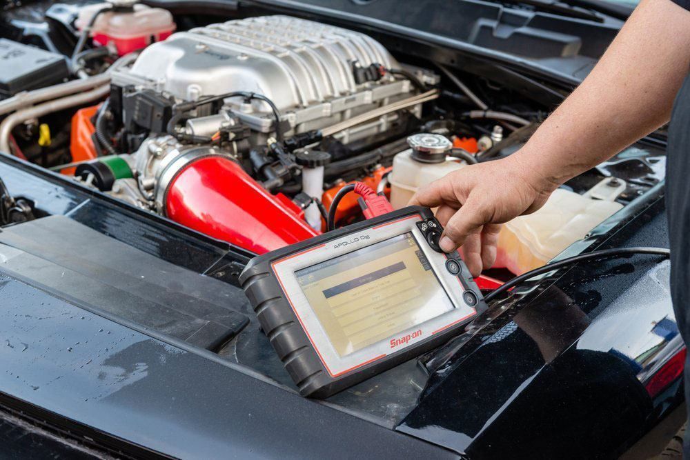 Person using a diagnostic scanner on a car engine in a garage