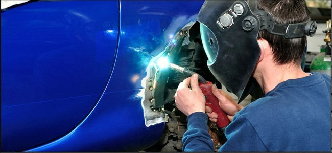 Man welding a blue car