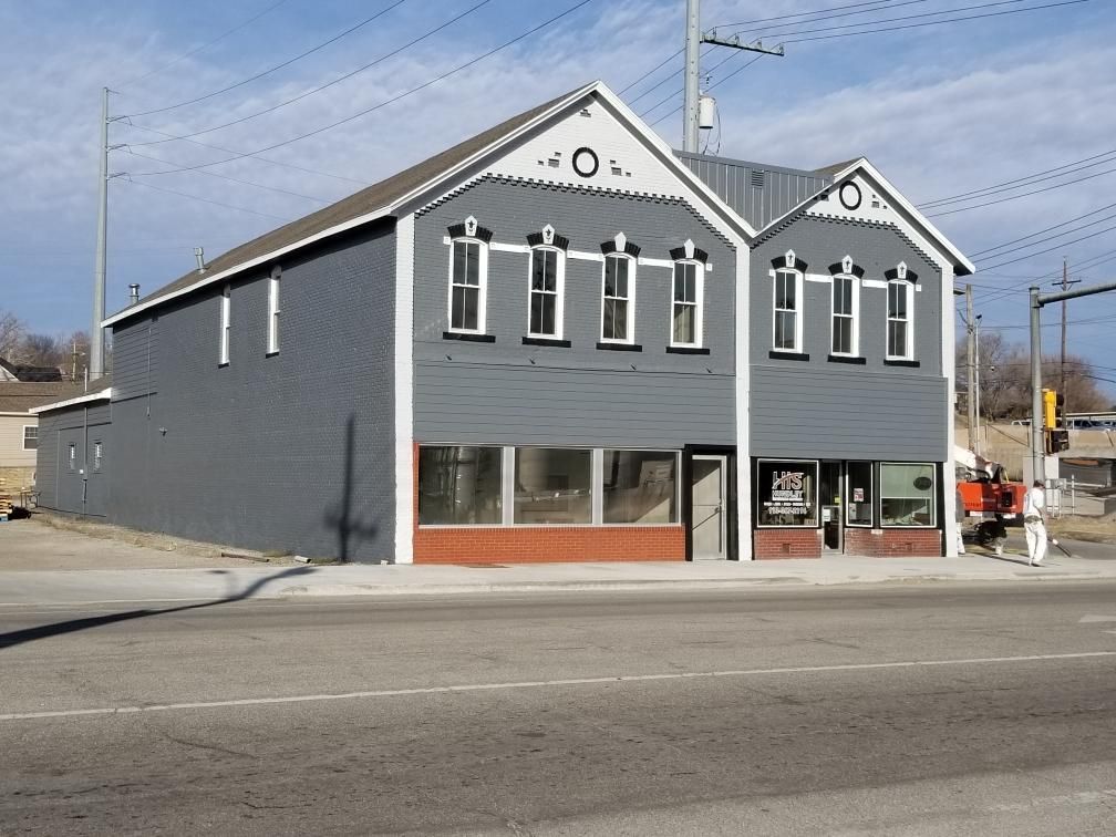A gray building with a white trim is next to a street