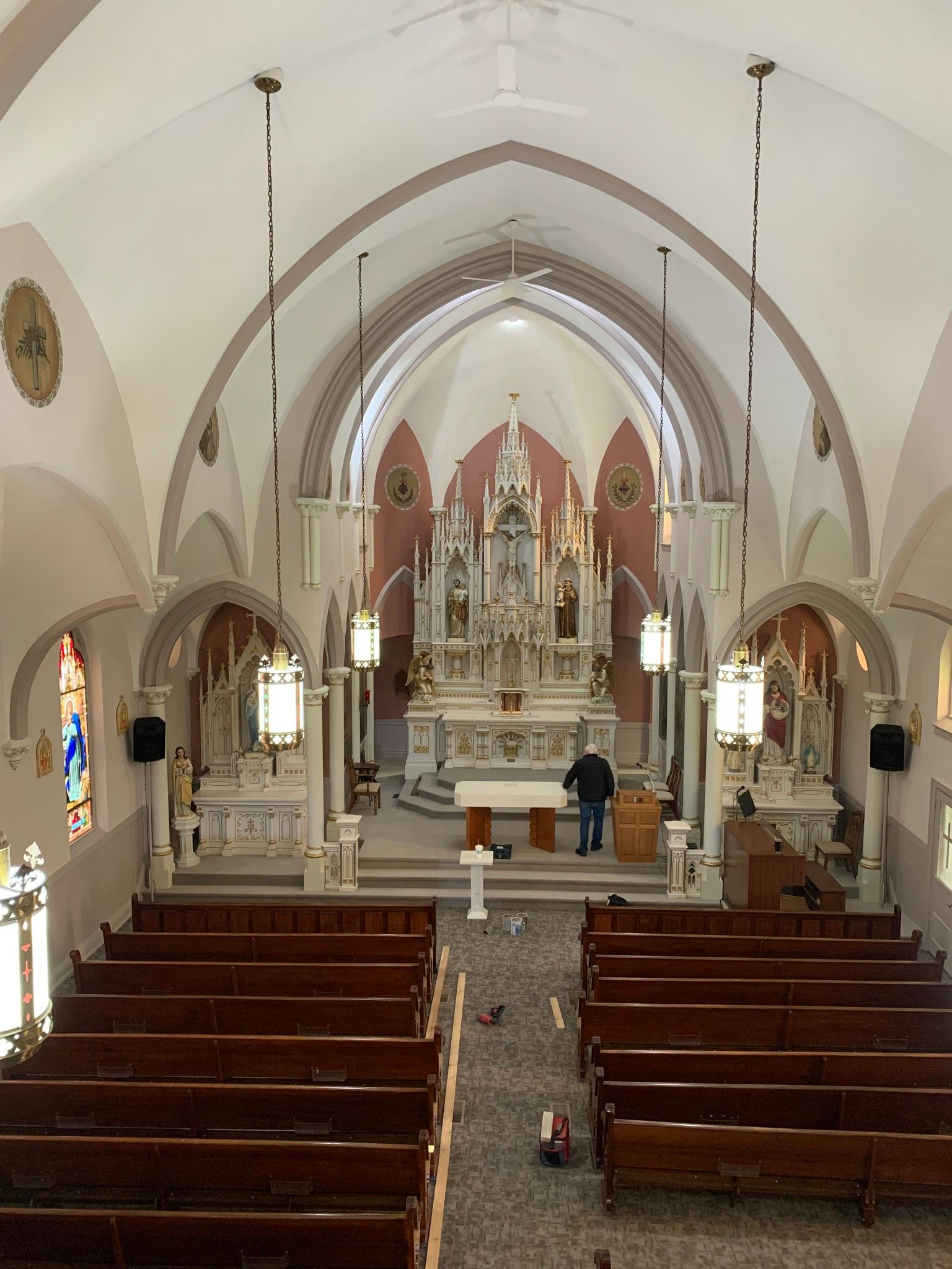 The inside of a church with wooden benches and a stained glass window.