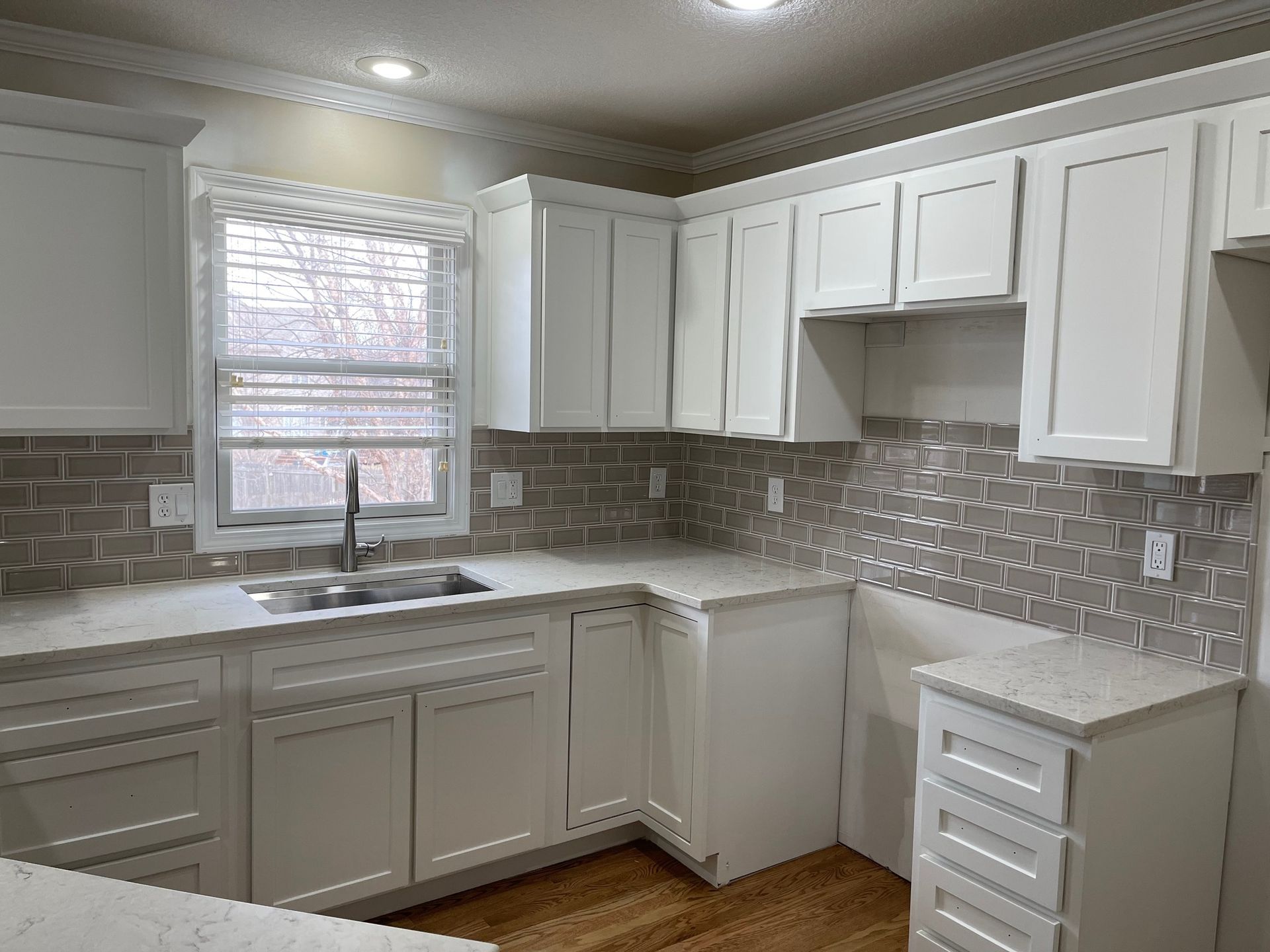 A kitchen with white cabinets, a sink, and a window.
