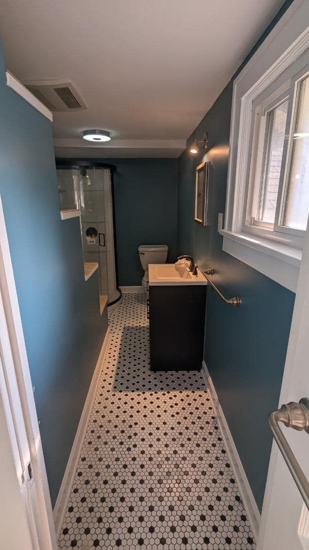 A bathroom with a toilet, sink, and window.