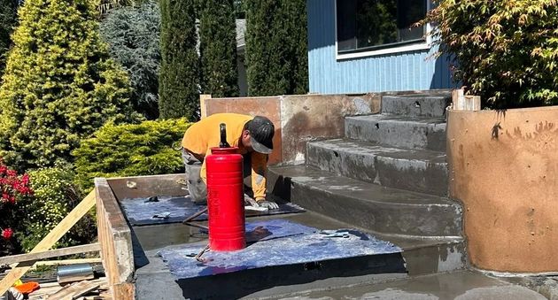 Worker kneeling on a porch, cleaning or repairing the steps.