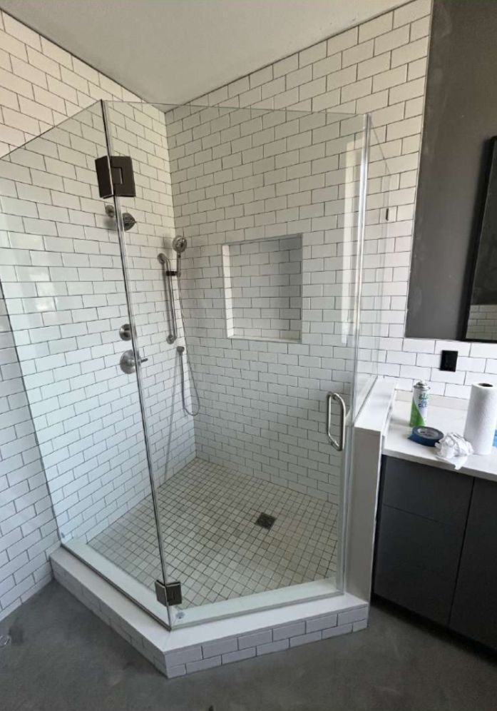 Modern bathroom with a glass-enclosed shower, white subway tile walls, and a gray vanity.